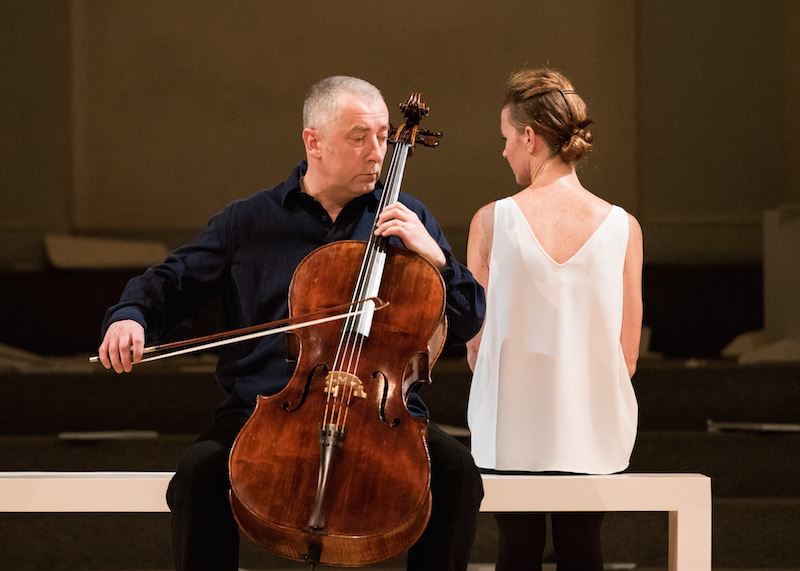 Jean Butler and Neil Martin sit on a white bench as Martin plays the cello